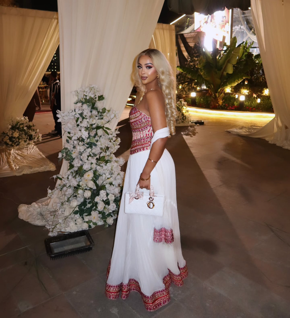  Woman posing in a white, strapless modern Habesha dress with pink and red traditional woven embroidery.