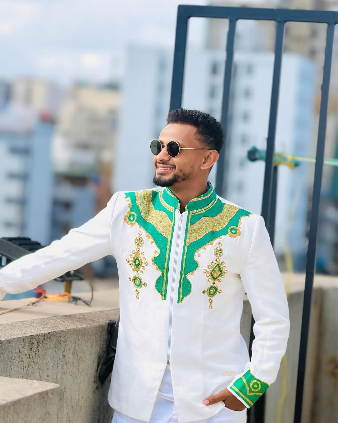 Man wearing a Ethiopian Men’s Habesha Shirtwith green details on a rooftop.