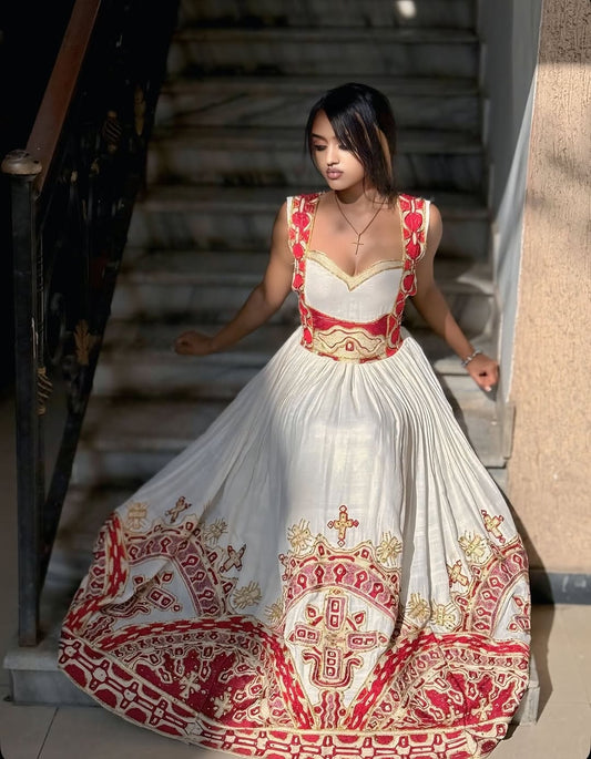 Woman wearing a red and white Traditional Ethiopian Dress embroidered dress walking outdoors.