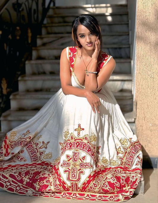 Woman in a white and red Traditional Ethiopian Dress sitting on steps.