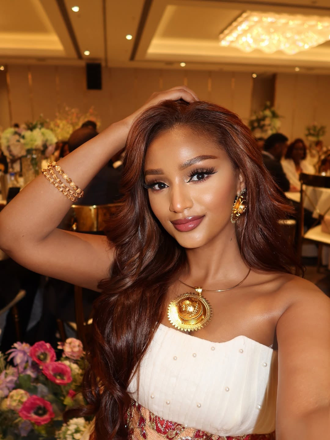 Woman with long, wavy hair posing  with Ethiopian Traditional Dress floral decorations.
