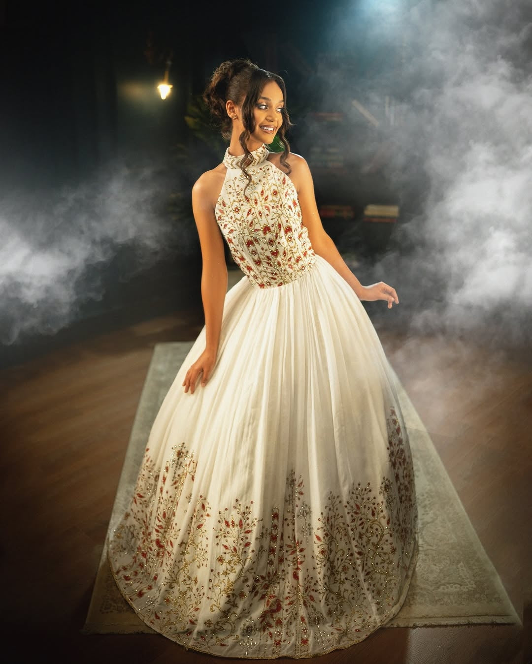 Woman in a floral evening Habesha dress  standing on a stage with smoke effects