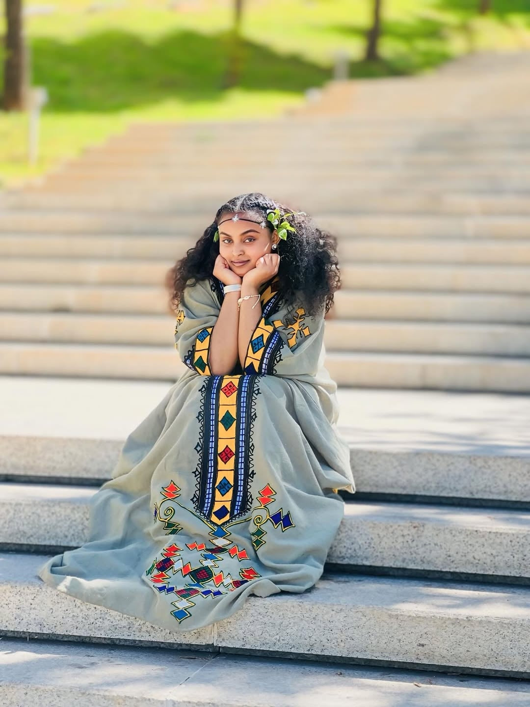 Woman in an embroidered Ethiopian dress sitting on steps outdoors