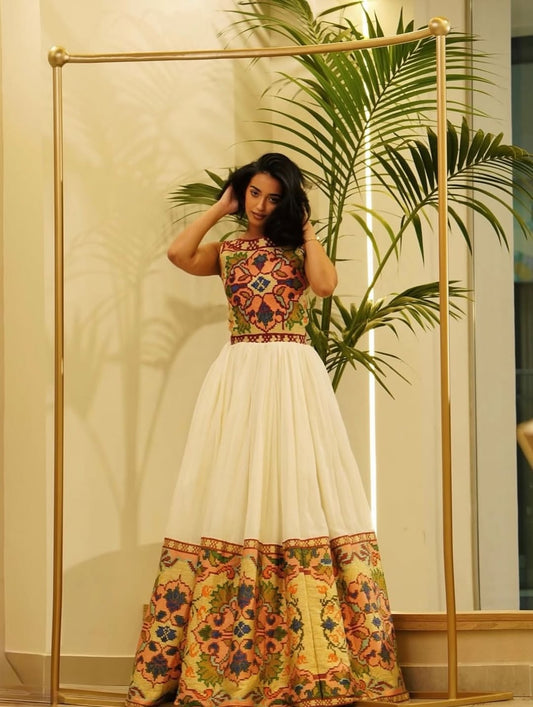 Woman wearing a colorful Ethiopian Traditional Dress with a floral pattern indoors.