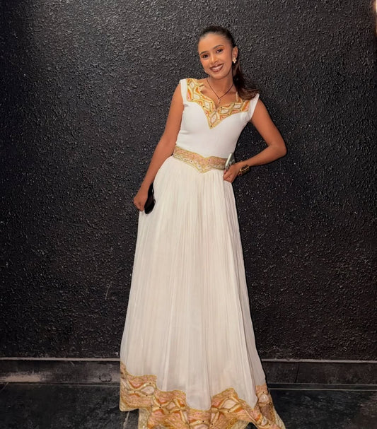 Woman in a white and gold Ethiopian traditional dress  posing against a black background