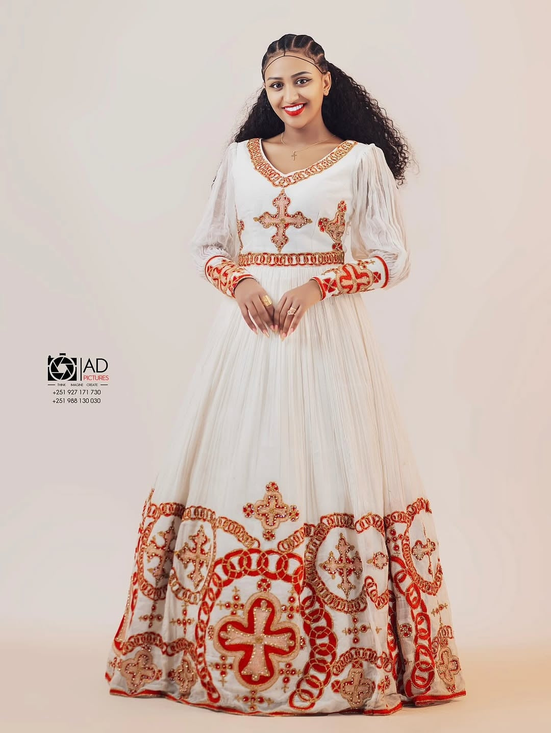 Woman wearing a white habesha dress with red embroidery on a plain background