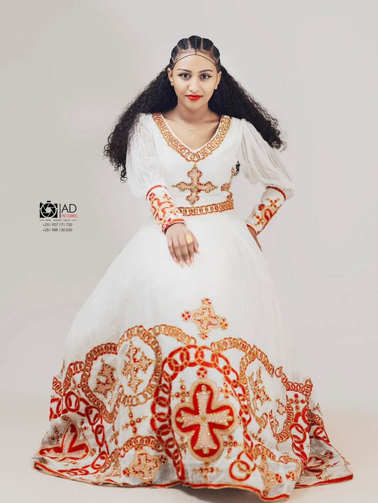 Woman wearing a white habesha dress with red and gold embroidery on a plain background