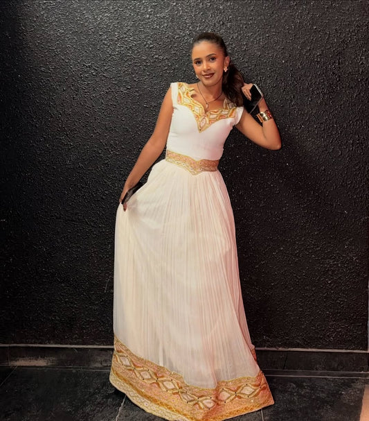 Woman in a white and gold traditional outfit against a black background