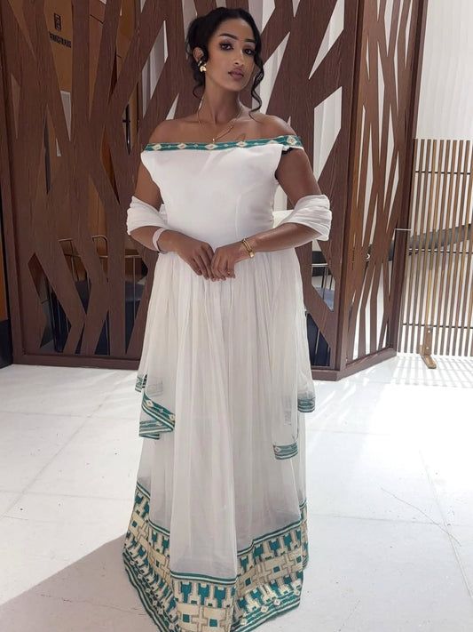 Woman wearing a white and green traditional outfit indoors.