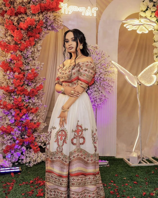 Woman in Habesha Wedding  Dress standing in front of floral decorations and archway