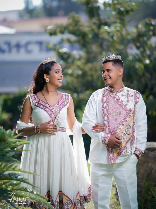 Two couple in Ethiopian Wedding Outfit attire standing outdoors with greenery in the background