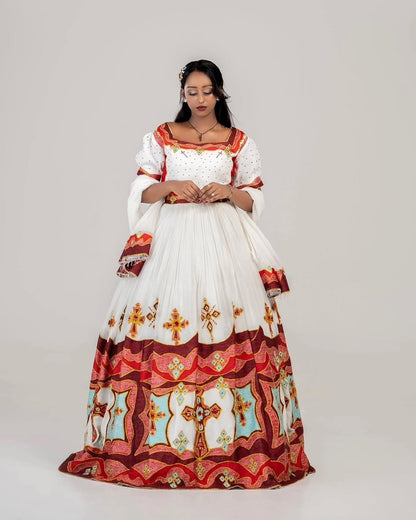 Woman wearing a traditional habesha dress with intricate patterns on a plain background