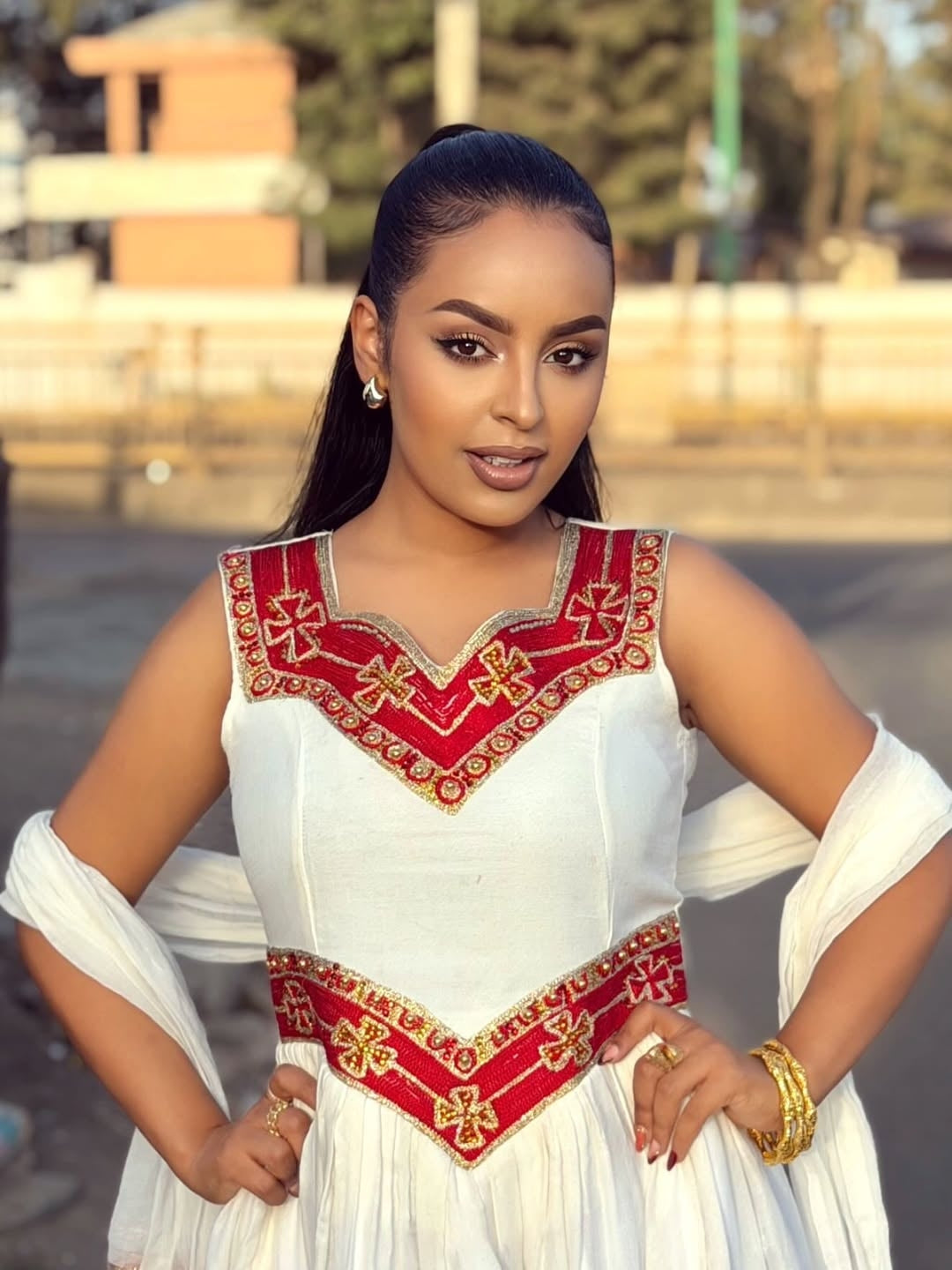 Woman wearing a  traditional Red Habesha Libs with gold accents outdoors.