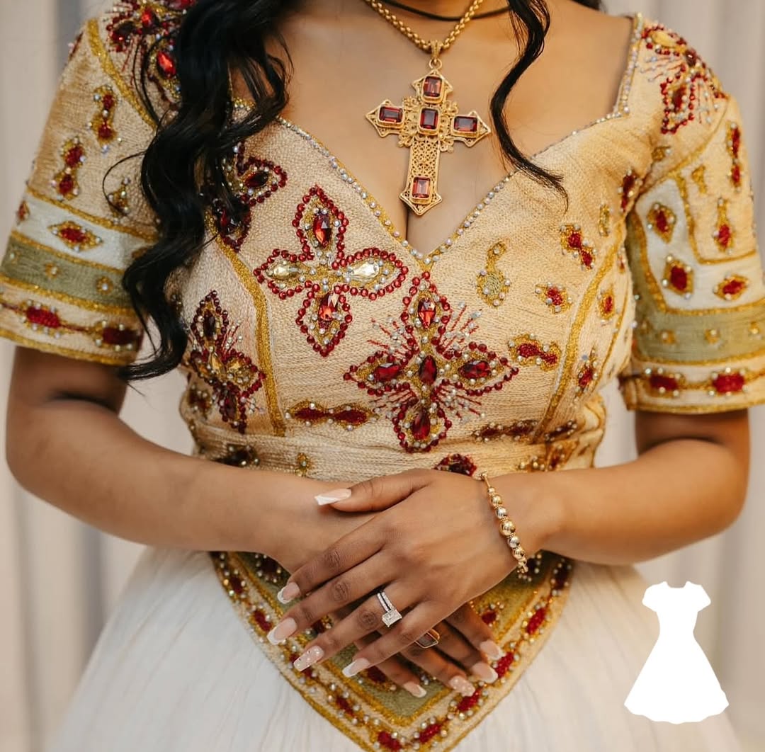Woman wearing a intricately designed Ethiopian traditional dress with floral patterns and a cross pendant necklace.