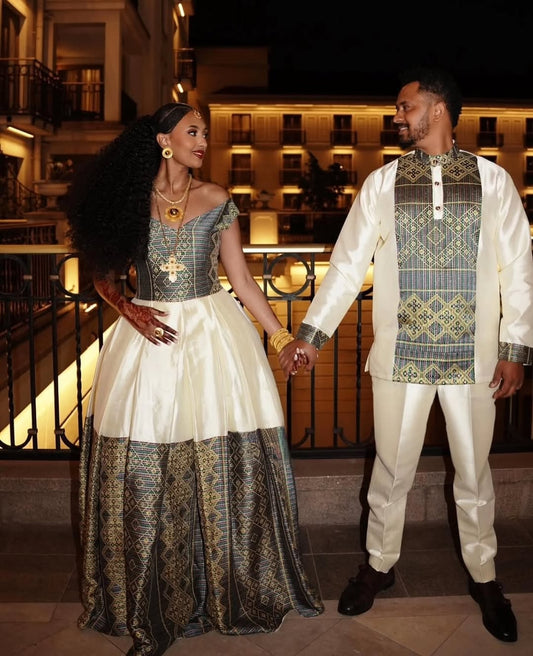Couple in Ethiopian traditional wedding attire standing on a balcony at night.