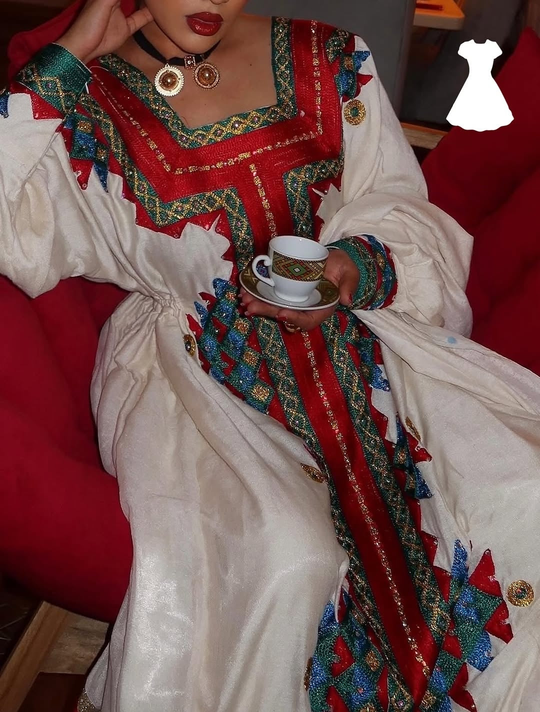Person wearing a colorful traditional Ethiopia traditional dress with a red and white background