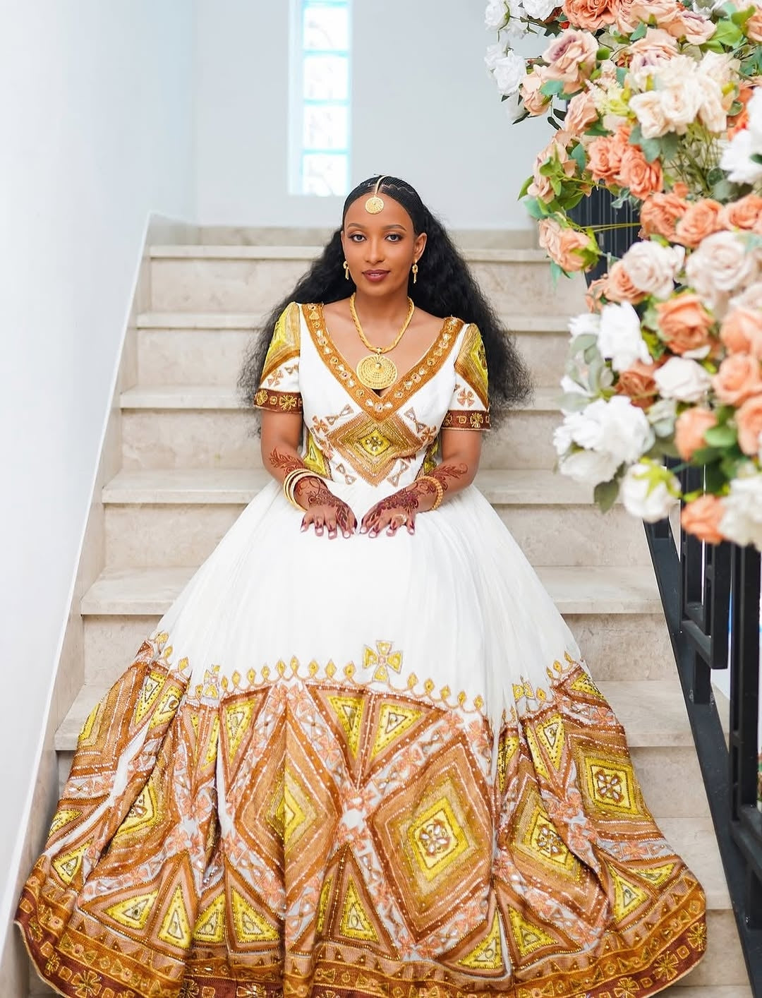 Traditional Habesha bridal dress photographed on elegant, decorated stairs.