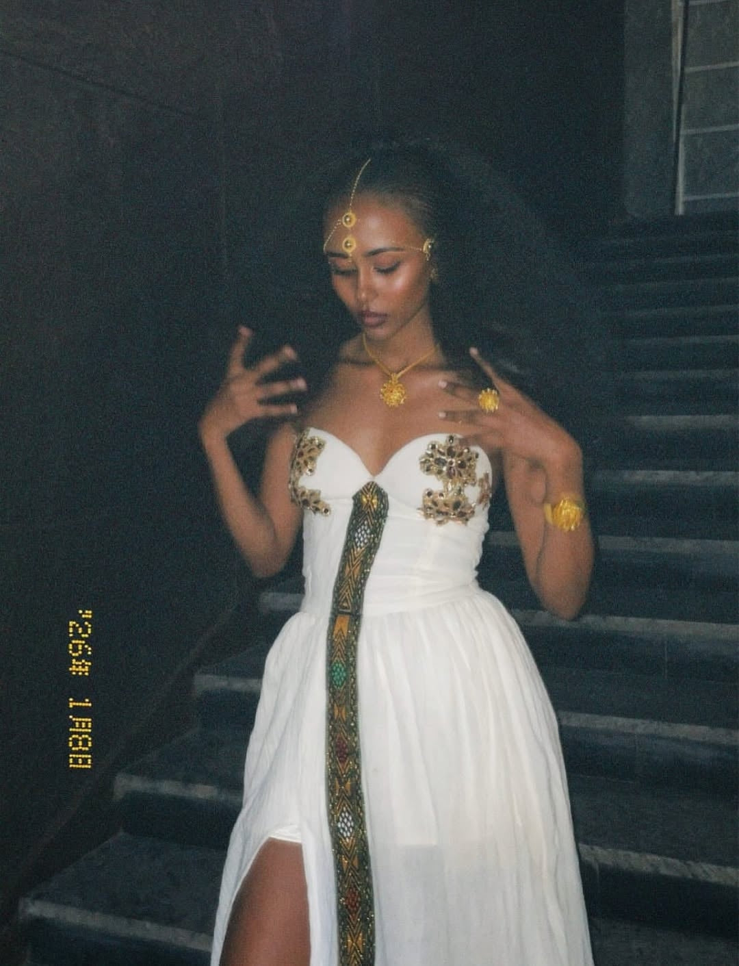 Woman in a Ethiopian traditional dress dress with gold accents on a staircase