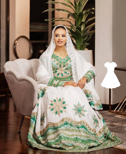 Woman in a white and green embroidered traditional Ethiopian traditional wedding dress sitting on a chair.