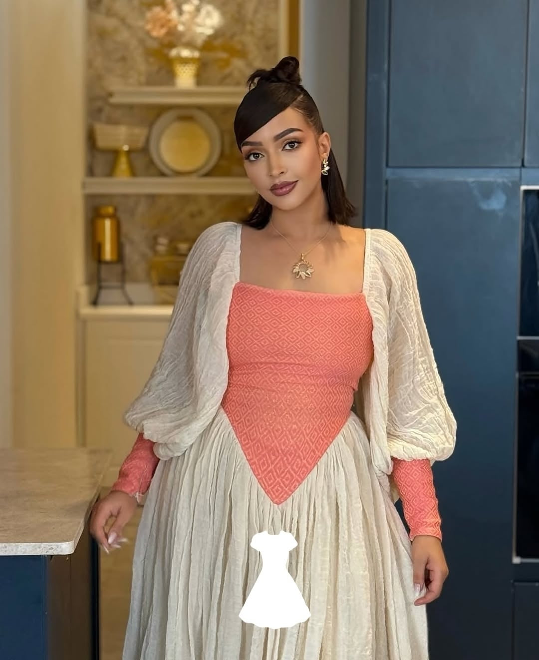 Woman wearing a pink Ethiopian traditional dress and beige in a kitchen setting