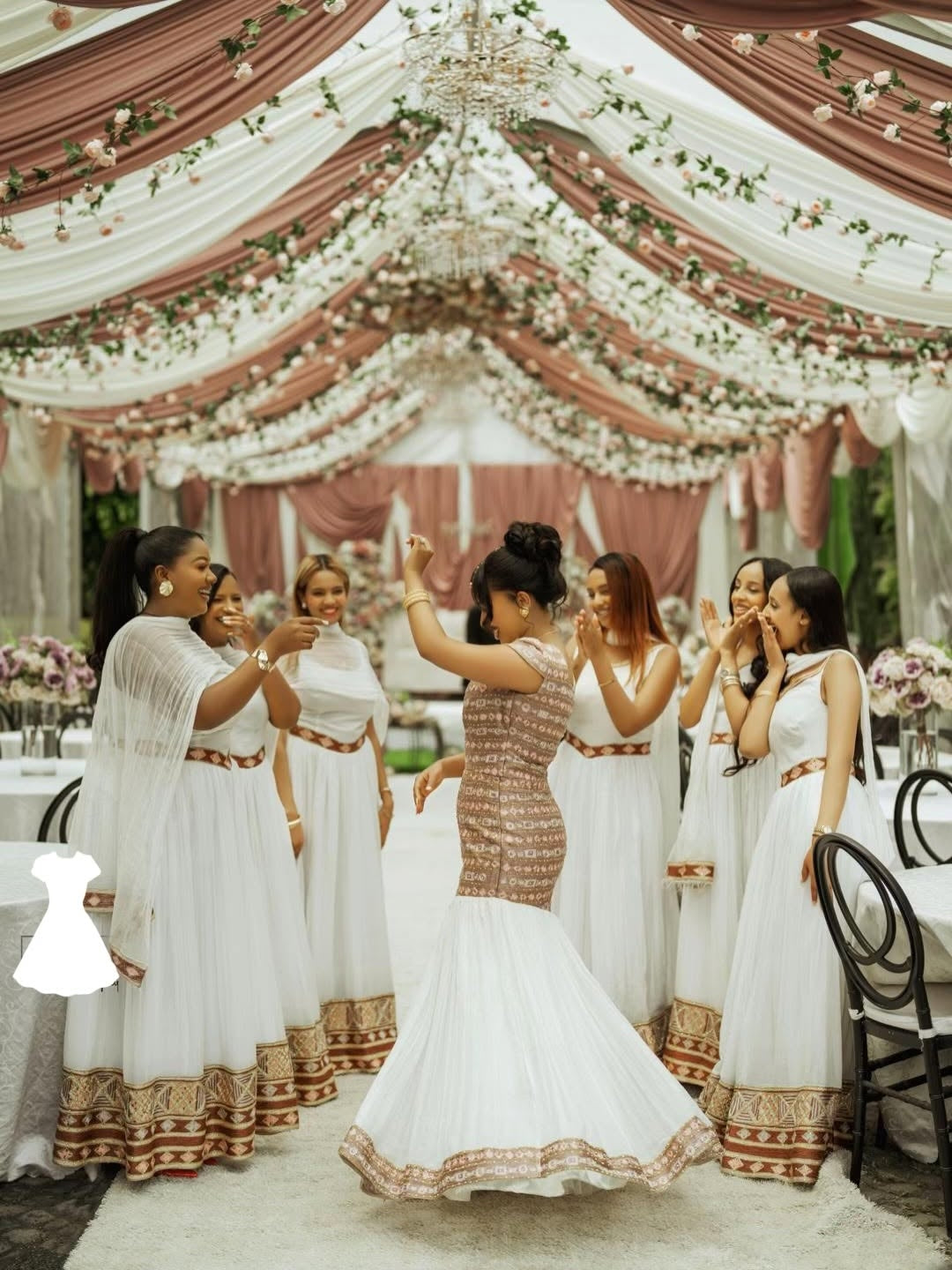 Woman in a white and gold Habesha Wedding Dress dancing in a decorated indoor setting with floral arrangements.