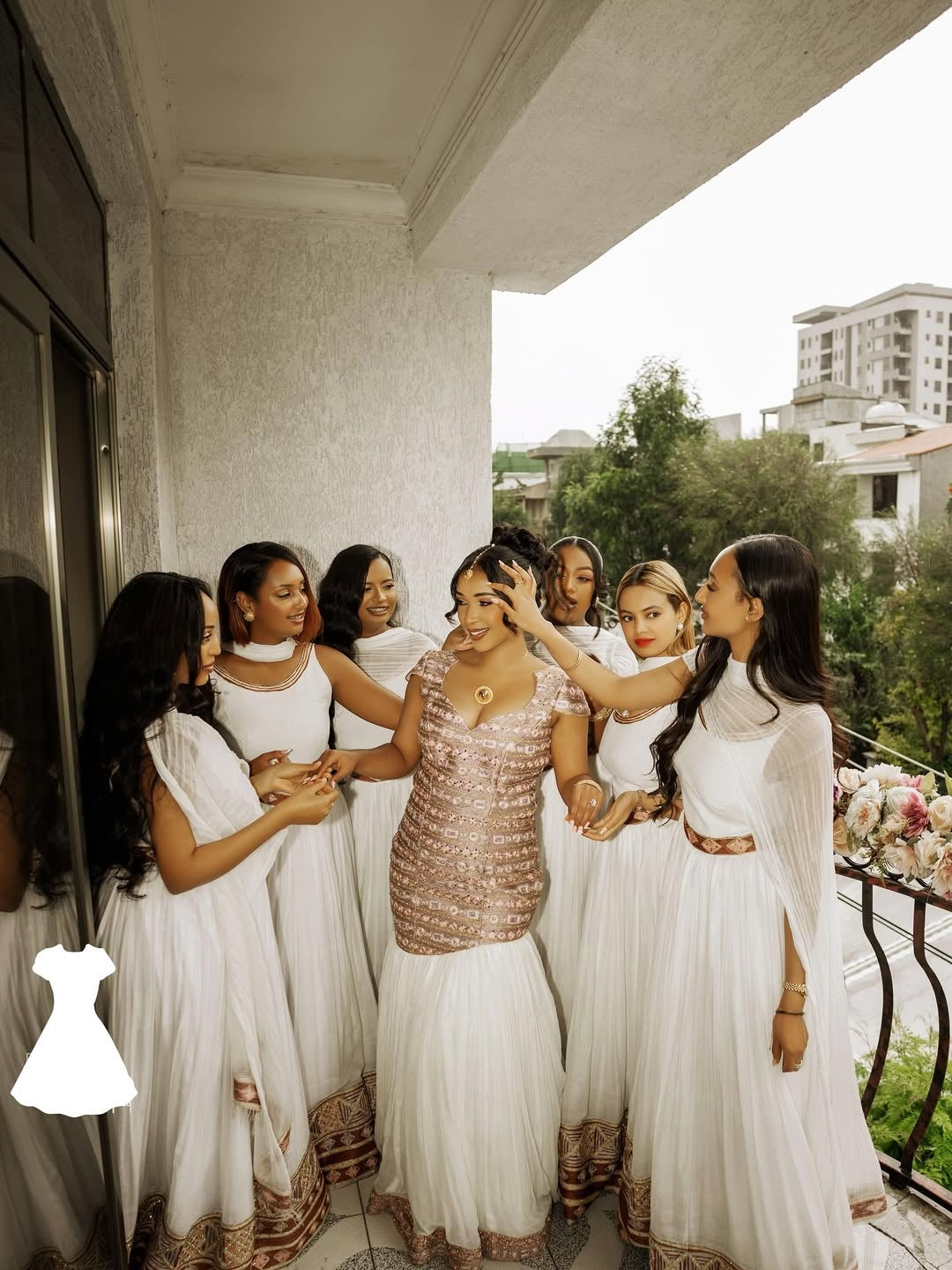 Group of women in white Habesha Wedding Dress on a balcony with a cityscape in the background