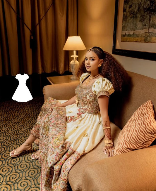Woman in Ethiopian Wedding Dress outfit sitting on a couch in an indoor setting