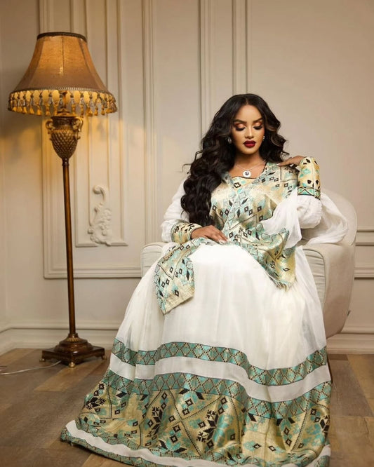Woman in a Habesha Libs sitting on a chair in an elegant room.
