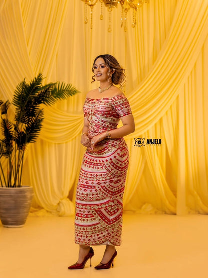 Woman in a patterned Habesha Kemis standing against a yellow curtain backdrop with a plant to her left.