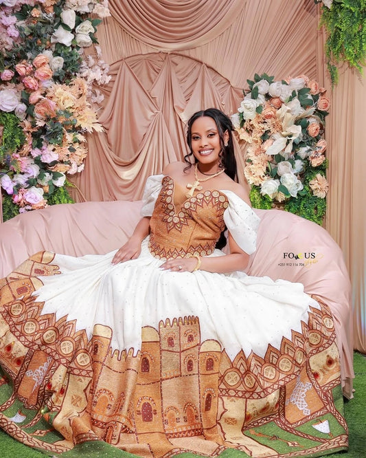 Woman with Habesha Wedding Dress in a decorated room with floral arrangements and a large chair.