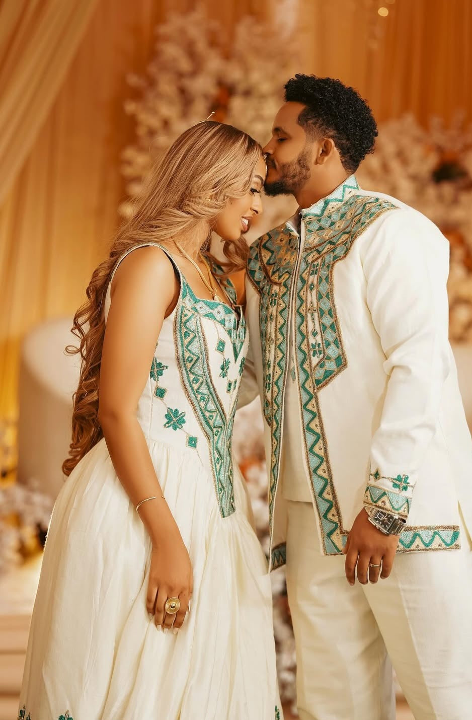 Couple in habesha wedding attire embracing in a decorated indoor setting