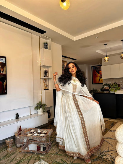 Woman in a white traditional outfit standing in a modern living room.