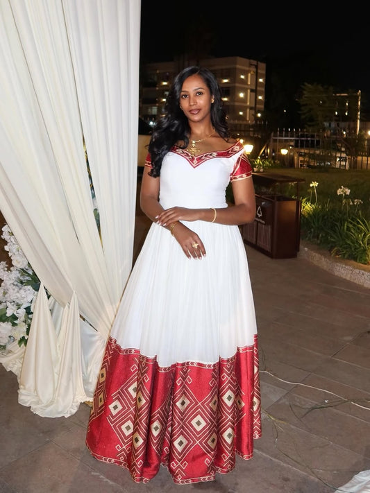 Woman in a white and red Ethiopian Libs   standing outdoors at night.