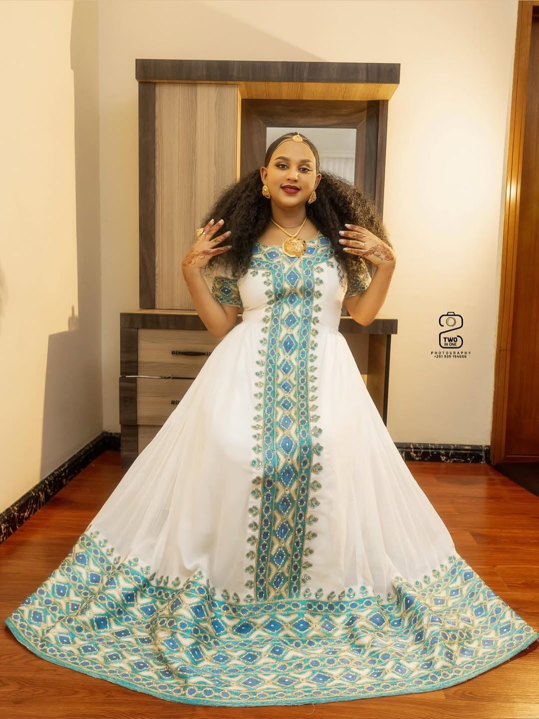 Woman wearing a white and blue embroidered Ethiopian Libs in a room.
