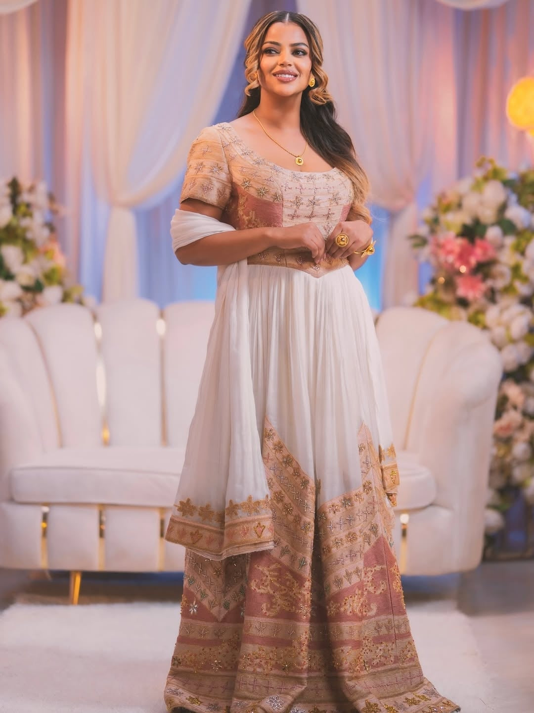 Woman in traditional outfit with floral decorations and white chairs in the background