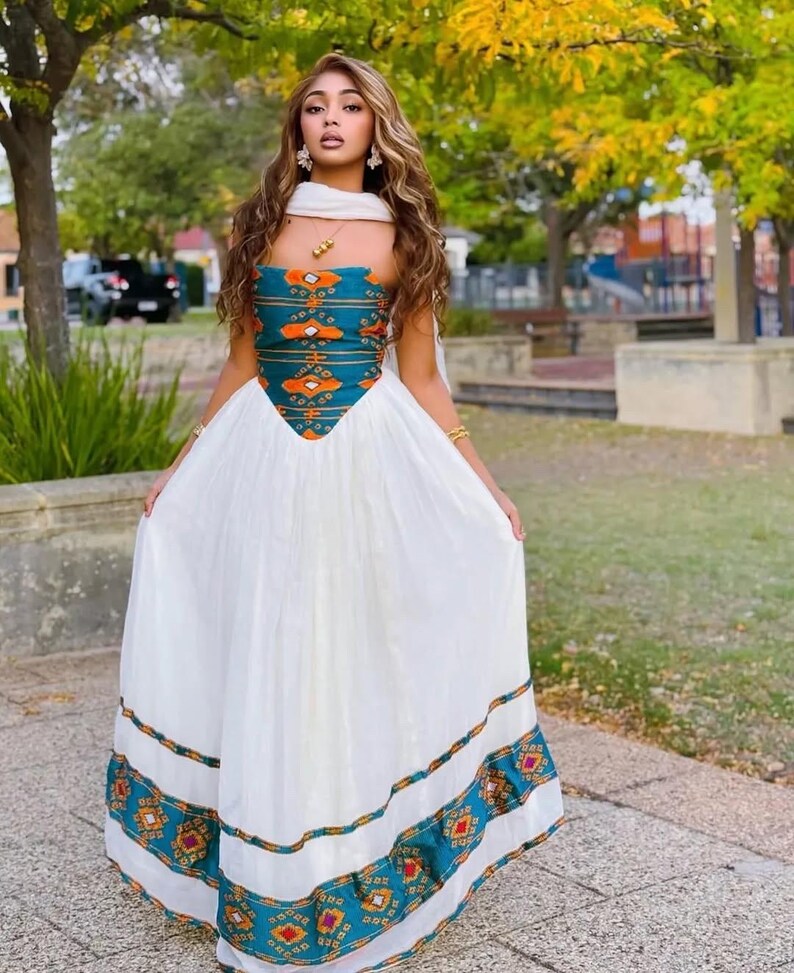 Woman wearing a Teal Ethiopian Dresswith a white overlay in an outdoor setting