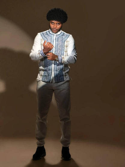 Person wearing in Ethiopian Men’s Shirt patterned jacket and light pants against a brown background