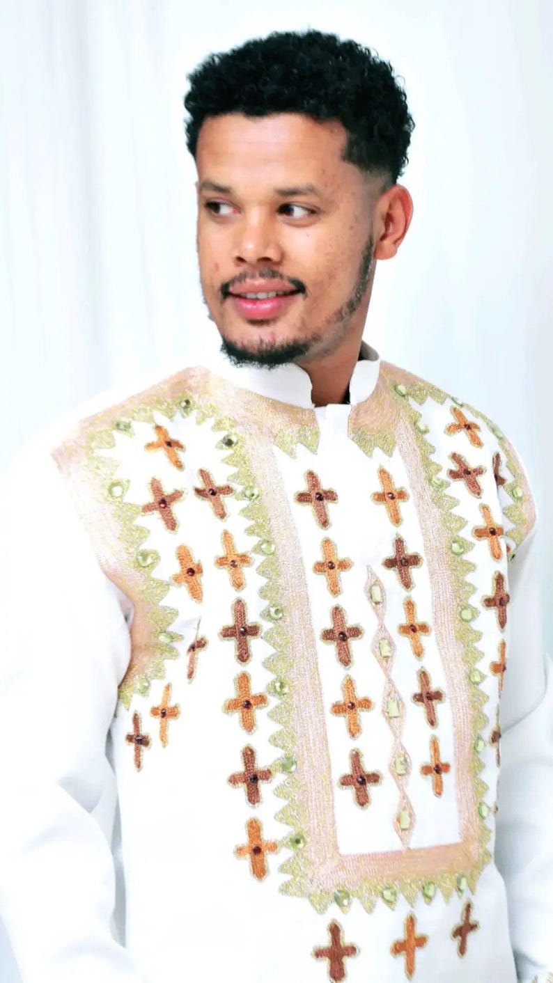 Man wearing a Habesha Men’s Traditional Outfit with intricate patterns on a white background