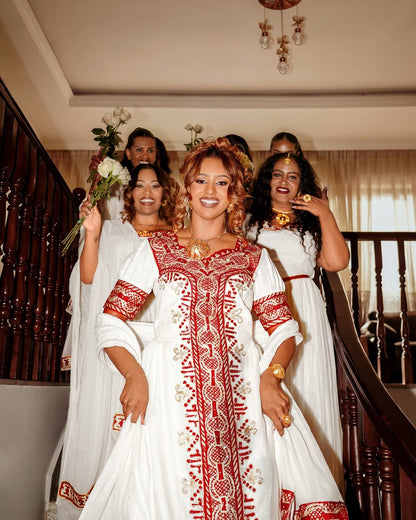 Woman in a red and white traditional Traditional Eritrean Style standing in a staircase with friends.
