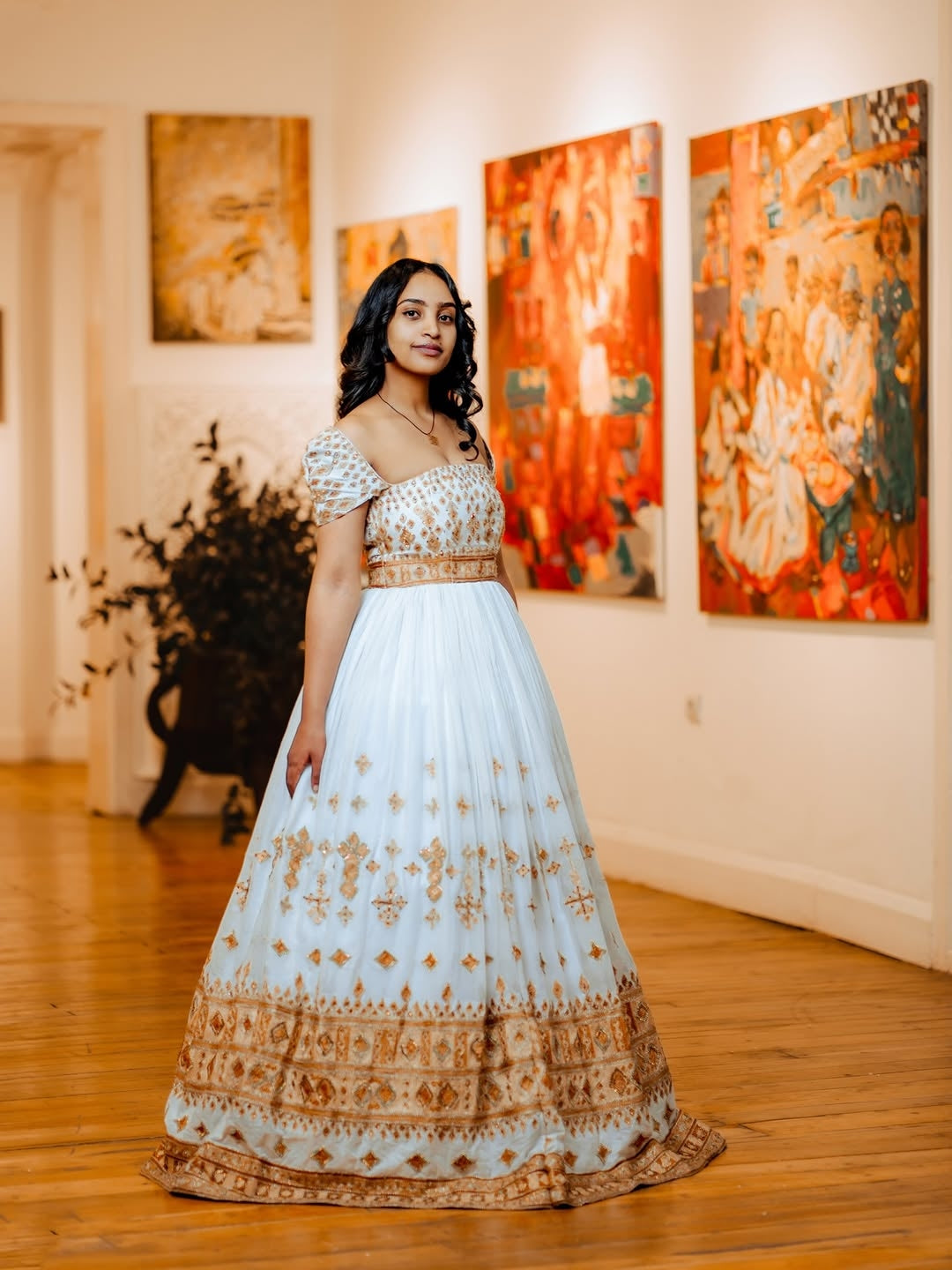 Woman in a white and gold traditional Gold Unique Ethiopian Wedding Matching Couple Set for Her and Him –  standing in an art gallery.