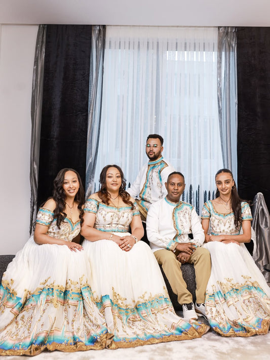 Family of five posing together in matching Ethiopian dress with a plain background