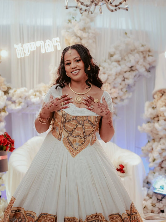 Woman in a Gold Ethiopian Wedding Kemis with floral decorations in the background