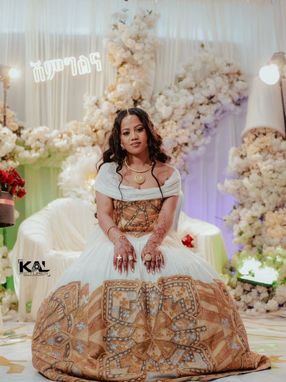 Woman in a decorated indoor setting with floral arrangements and Gold Ethiopian Wedding Kemis.