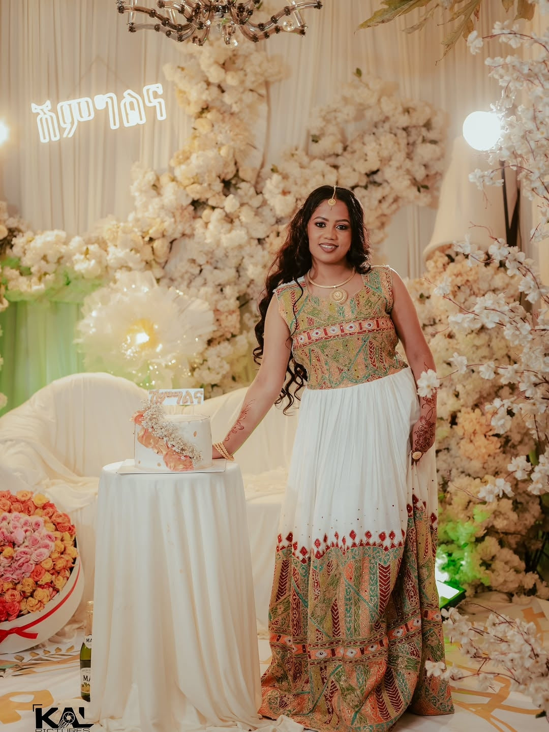 Woman in a decorated indoor setting with floral arrangements andRed Luxury Habesha Wedding Dress.