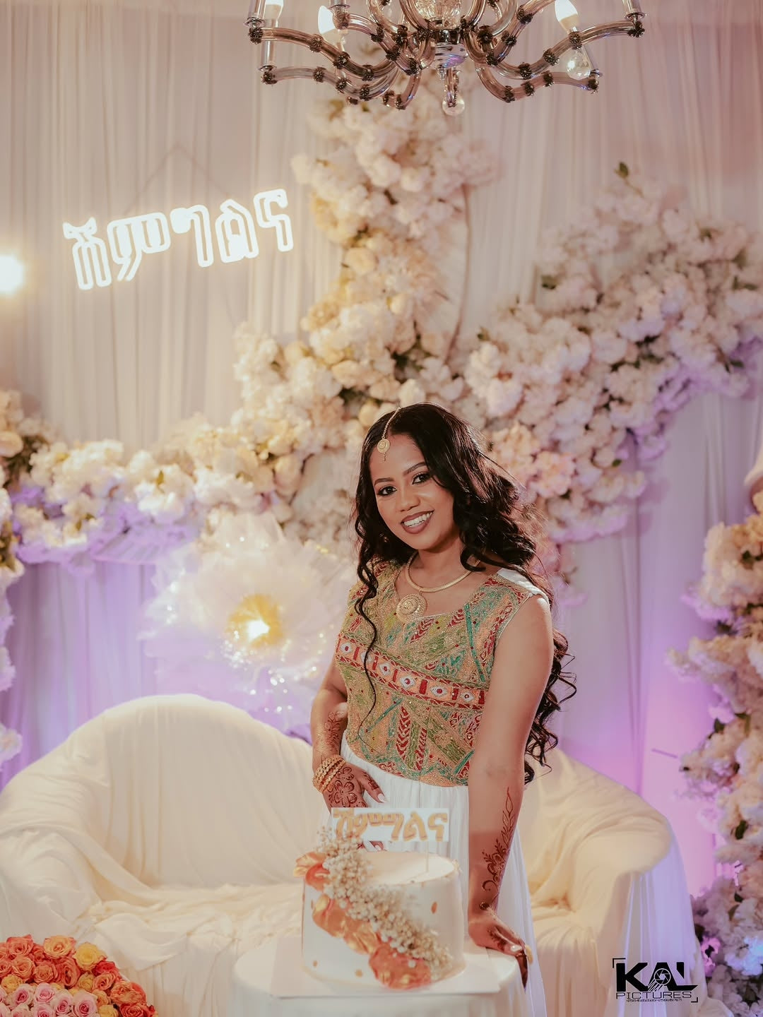 Woman with Red Luxury Habesha Wedding Dress in a decorated room with flowers and a chandelier