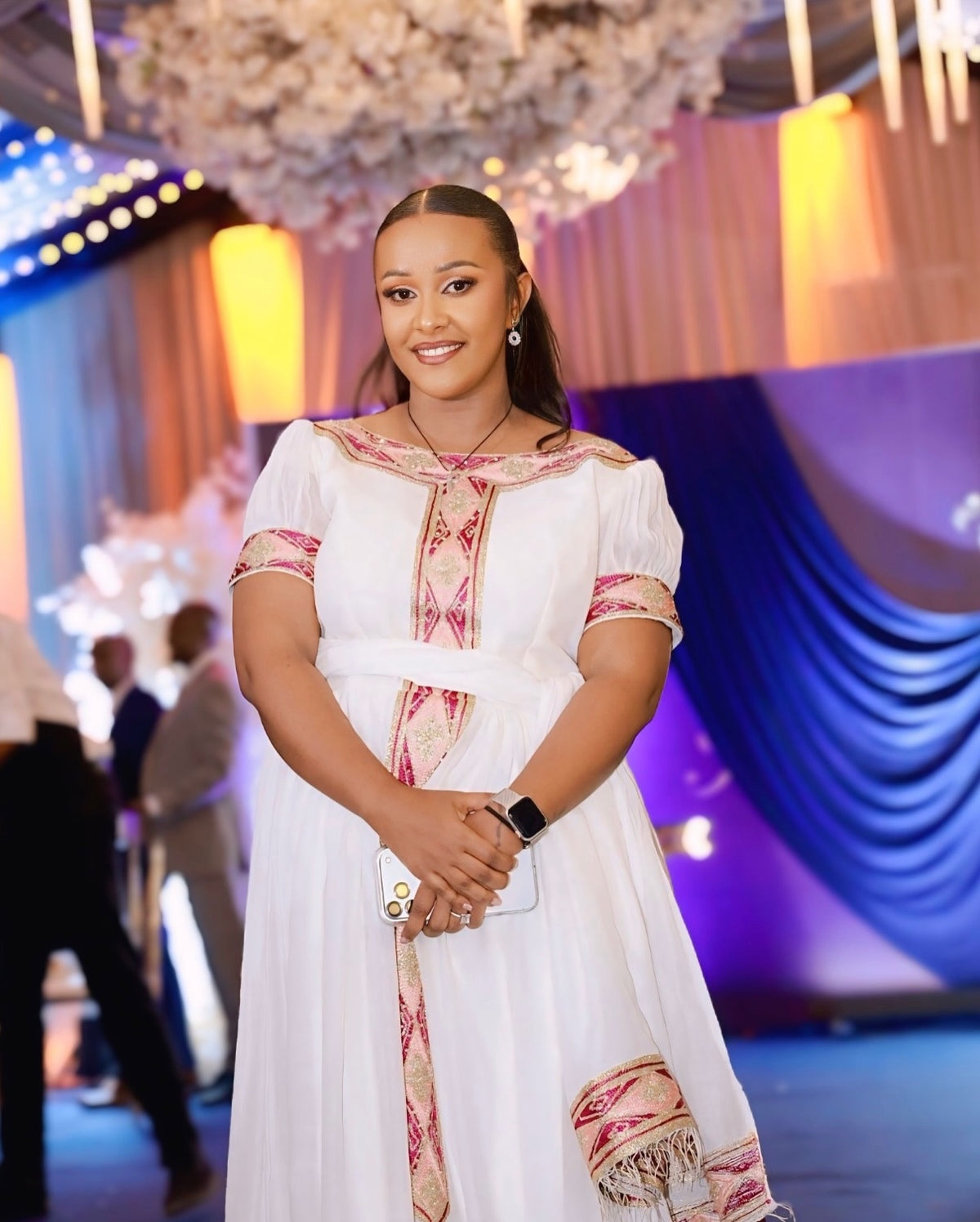 Woman in a white and red habesha  kemis standing in a decorated indoor setting