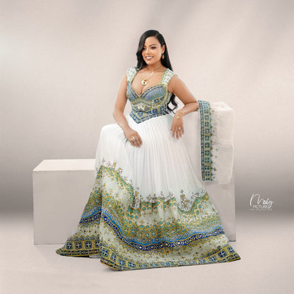 A woman models a traditional habesha Wedding dress with a white skirt, blue and gold embroidered bodice, and a matching dupatta draped over a white block against a neutral studio background.