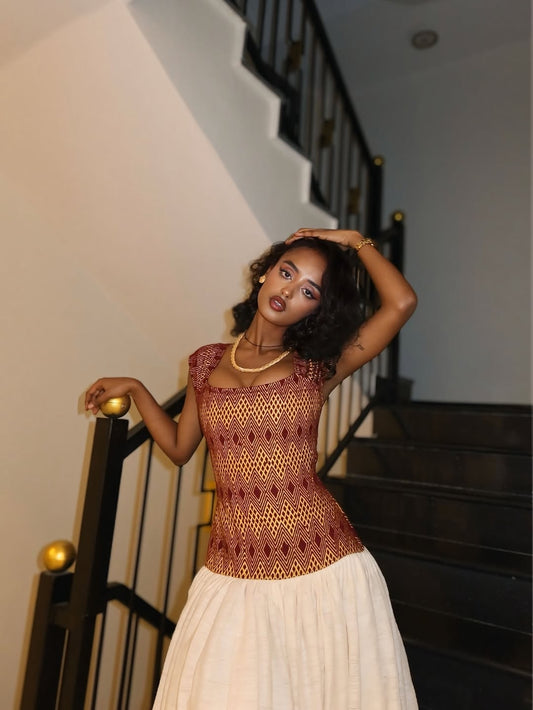 Woman in a patterned top and white Red Habesha Kemis Full Tibeb standing on a staircase