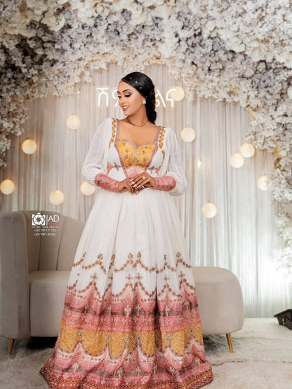 Woman in a white and colorful Ethiopian Habesha Couple Set standing in a decorated room with flowers and lights.