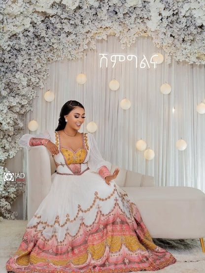 Woman in a colorful Ethiopian Habesha Couple Set sitting on a couch with floral decorations and lights in the background